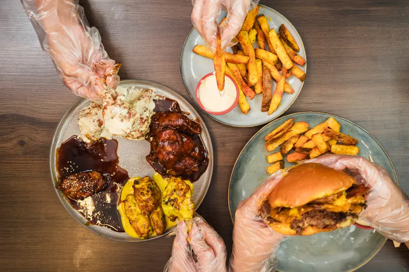Amigos compartiendo alitas, papas y hamburguesa en Wings Express